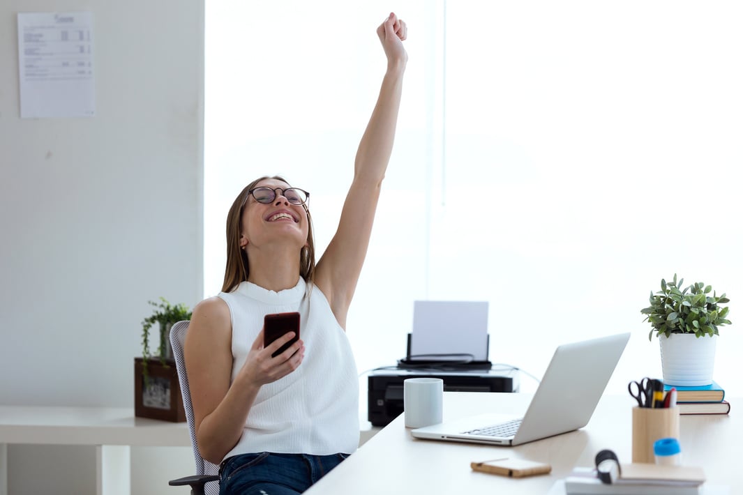 Business Young Woman Celebrating a Victory While Working with Mo